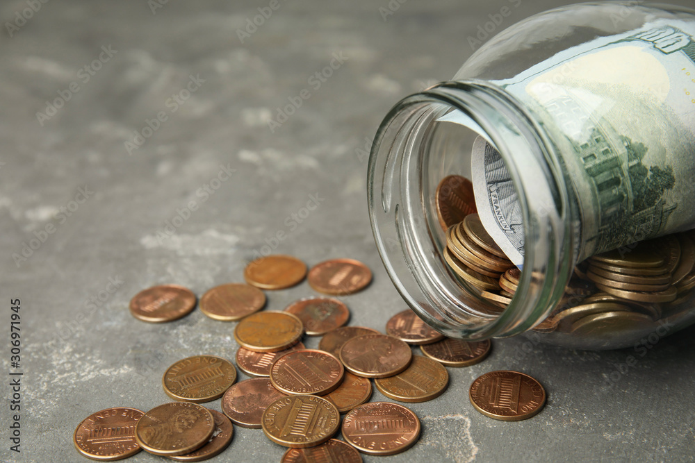 Overturned glass jar with money on grey stone table, closeup Overturned glass jar with money on grey stone table, closeup