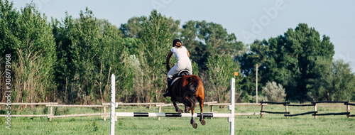 A woman jockey jumps a barrier on a horse in summer competitions.