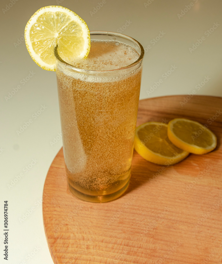 Lemonade in the glasses with lemon slice and wooden board. Pour the lemonade.  White background.
