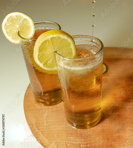 Lemonade in the glasses with lemon slice and wooden board. Pour the lemonade. White background.