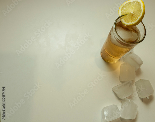 The glass of lemonade with slice of lemon and ice around. The cold drink.