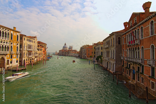 Landscape of Grand Canal with turquoise water at sunny day. Medieval colorful buildings and palazzo along the canal. Basilica Santa Maria della Salute in the background. Travel and tourism concept