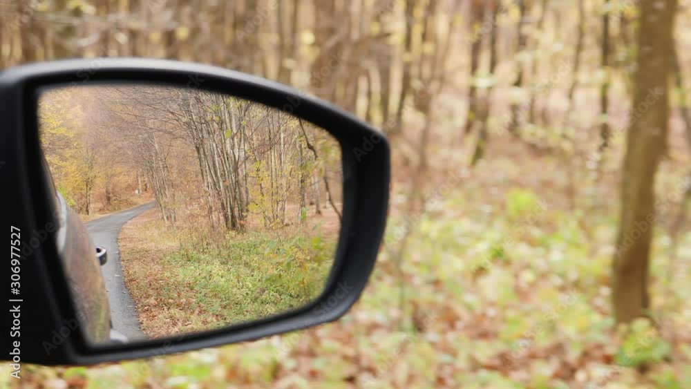 Autumn forest reflected in the mirror of a car cruising on road Autumn forest reflected in the mirror of a car cruising on road