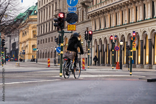 A cyclist stands and waits near a traffic light © Olya