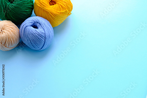 Mock-up made with bright color yarn clews on the blue background. Concept of amigurumi toy making, handicraft, knitting, hobbie. Can be used for posters