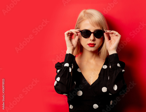 beautiful woman in sunglasses on red background