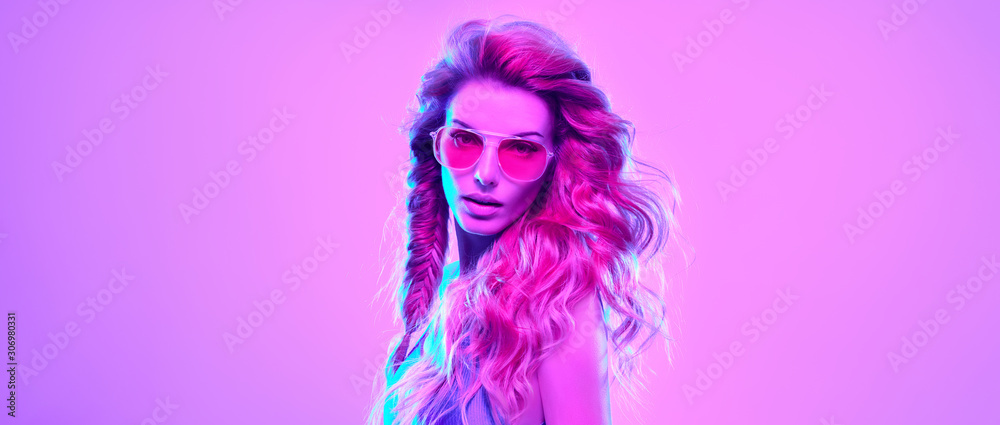 High Fashion. Gorgeous Party Girl in Pink neon. Young Beautiful Model woman, Trendy Disco hairstyle, makeup. Stylish Art Portrait. Creative colorful bright neon light. Night Club fashionable concept.