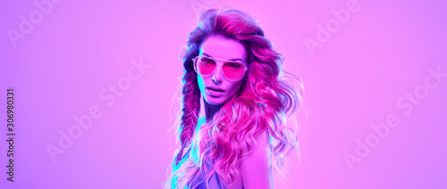 High Fashion. Gorgeous Party Girl in Pink neon. Young Beautiful Model woman  Trendy Disco hairstyle  makeup. Stylish Art Portrait. Creative colorful bright neon light. Night Club fashionable concept.
