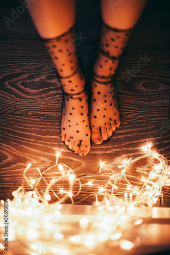 Female legs in socks with stars and christmas lights. On the eve of the holiday