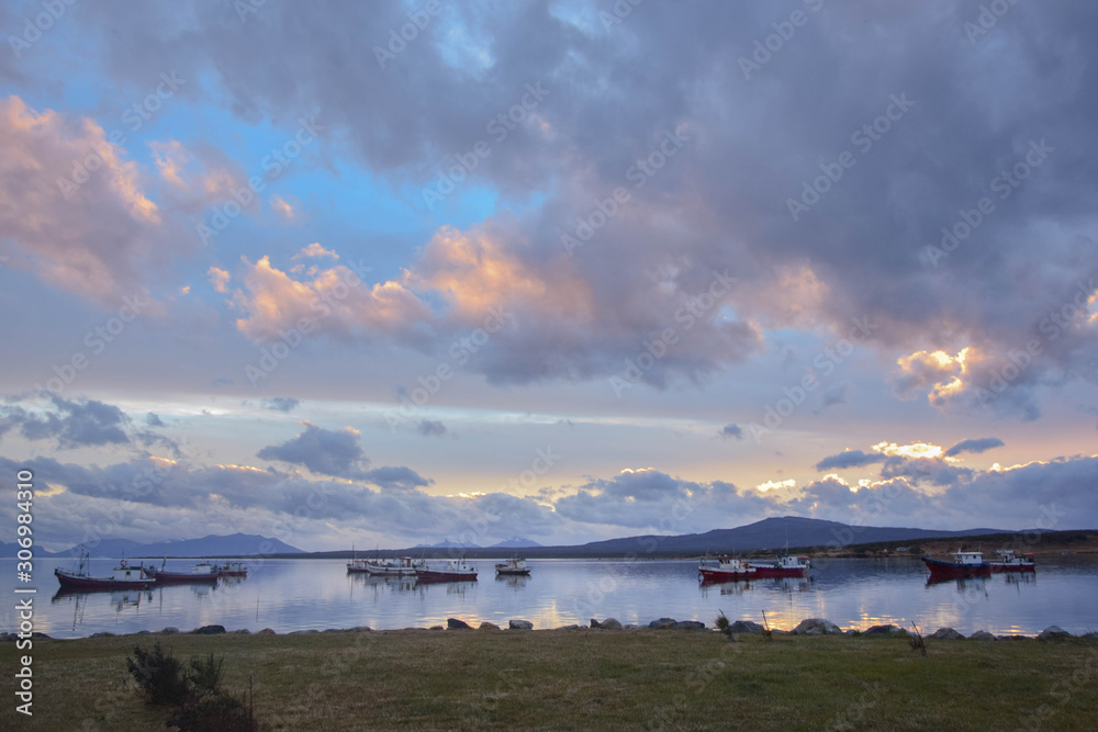 Several fishing boats in the bay in a cloudy sunset in Patagonia