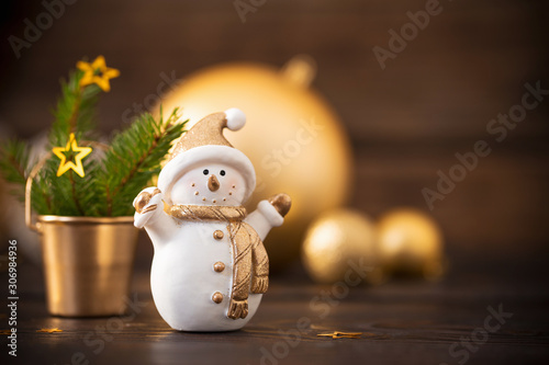 Christmas golden decorations and snowman on dark wooden backgrou