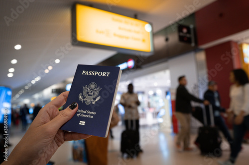Close up of woman holding an United States passport over a blurred airport background. Digital composite