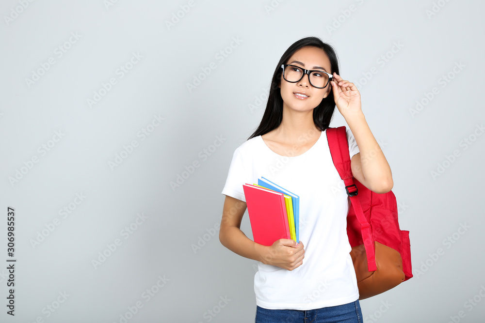 Young woman with books and backpack on grey background Young woman with books and backpack on grey background