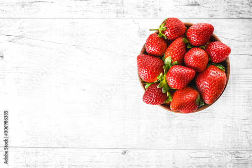 Ripe strawberries forest fruits in wooden bowl on white table. Fresh strawberry concept top view. photo