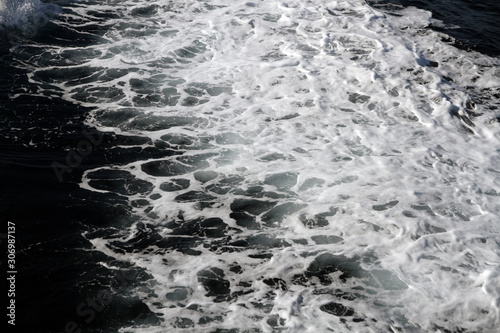 Weisser Schaum auf der Wasseroberfläche. Gischt am Ozean bei einer Fahrt mit dem Schiff. Wasser in Bewegung. Spur im Meer
