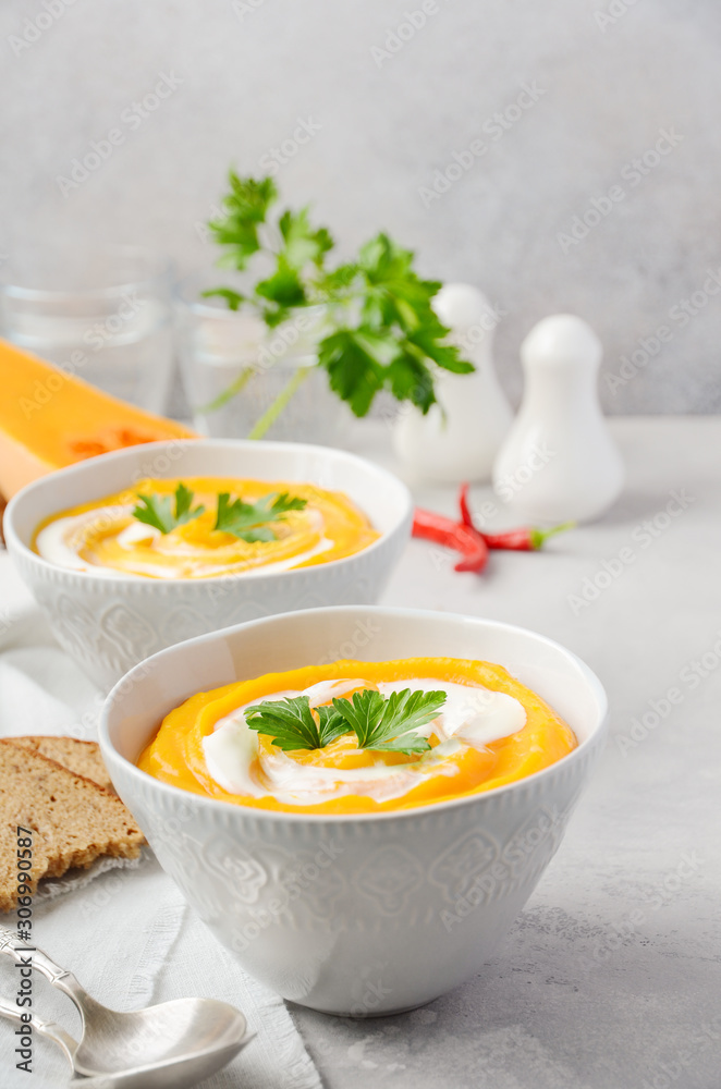 Pumpkin soup with cream and parsley on a gray concrete or stone background. Pumpkin soup with cream and parsley on a gray concrete or stone background.