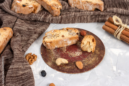 Tasty traditional Italian homemade biscotti or cantuccini cookies with hazelnuts, almonds and walnuts on a light gray background.
