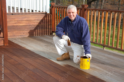 painter staining a deck in the spring
