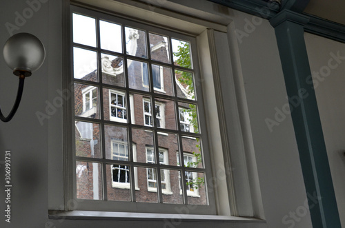 Amsterdam, the Netherlands. August 2019. Seen from inside the church of the city beguinage, through a large window one recognizes the typical facades of Dutch houses.