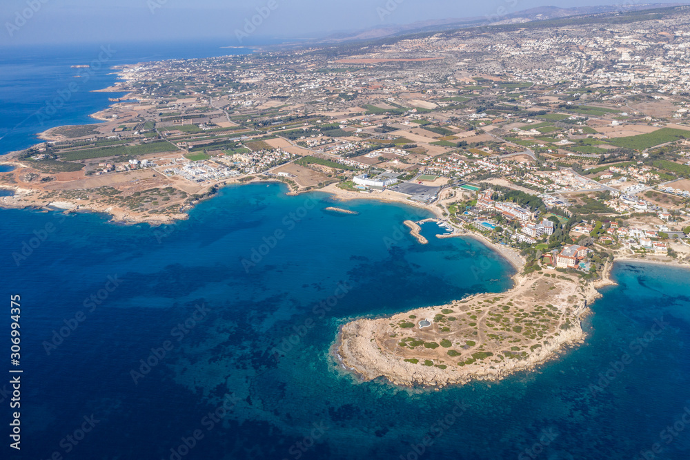 Aerial view of Coral Bay, famous place with sandy beaches near Paphos, Cyprus and rock cliffs with hotel on seaside. Idyllic mediterranean landscape from air.