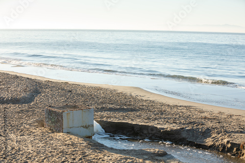 Stormwater exiting a drain on a sandy beach