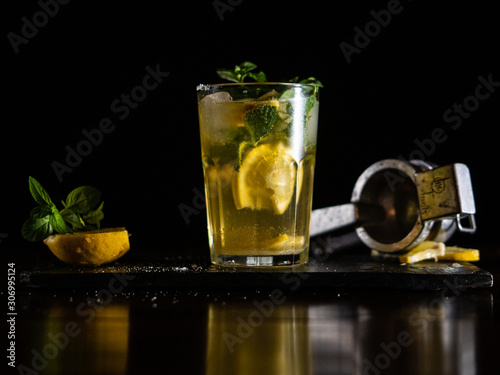 Photography Cuban mojito with lemon and mint leaves in a dark background shot at a cuban par