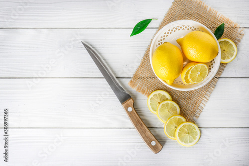 Yellow healthy fruits on wooden white table or background. Lemons cut on jute with knife  top view.