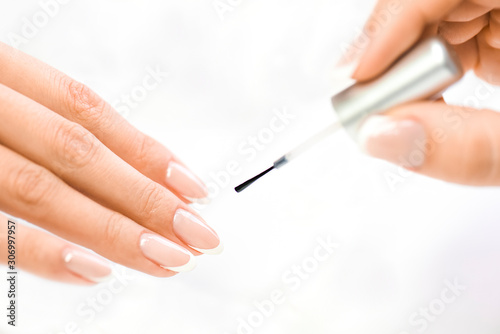 Beautician in luxury salon applying lacquer or varnish gel on nails..Manicure nail paint with brush or artist polish modelation technique on white background  isolation.