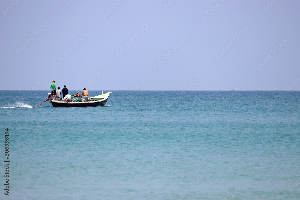 Motor boat with people sails in the ocean. Tropical seascape, fishermen in South East Asia Motor boat with people sails in the ocean. Tropical seascape, fishermen in South East Asia