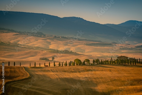Beautiful morning landscape with the rolling hills, cypress trees and mountains . Travel destination Tuscany, Val d'Orcia, Italy