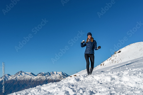 Smiling woman on a snowball fight competition at mountains, outdoor winter game with snow, copyspace
