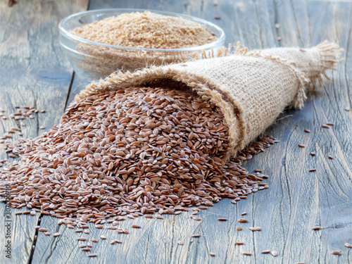 Flax seeds in linen cloth and miiled seeds in glass bowl on the wooden dark table. photo