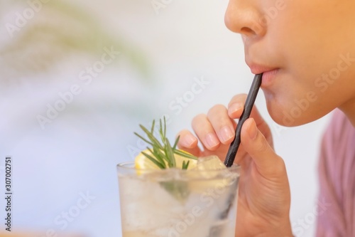 The girl uses a paper straw to suck lemon juice in cafe,soft focus