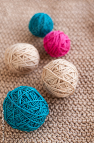 Bright balls of yarn lying on beige knitted plaid.