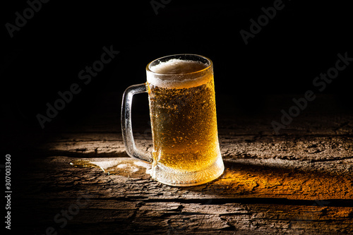 Beer. Cold Craft light Beer in a glass with water drops on the wooden table over the black background.