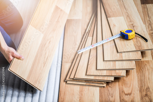 Man worker installing timber laminate floor with measure tools. Wooden floors house renovation.