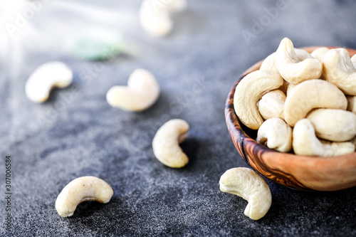 Cashew nuts in wooden bowl on dark stone table.