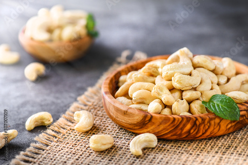 Cashew nuts in olive wooden bowl on dark stone table. Delicacies nut on black background.