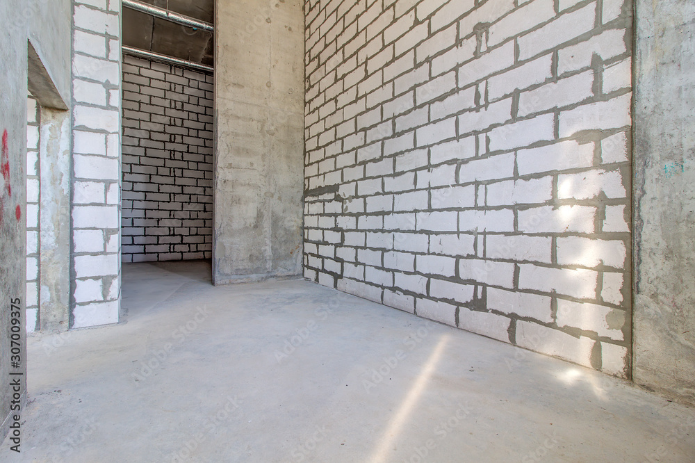 Monolithic brick basement wall. heating pipes lie on floor. New empty