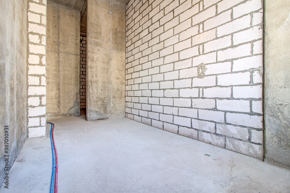 Monolithic brick basement wall. heating pipes lie on floor. New empty