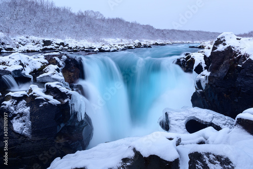 Hlauptungufoss in winter with azure water stream