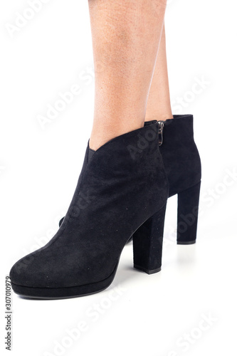 women's feet shod in black demi season high heeled ankle boots close up on a white background