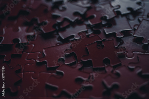 Bunch of dark red Pieces of the puzzle. Close up. Blurred background.