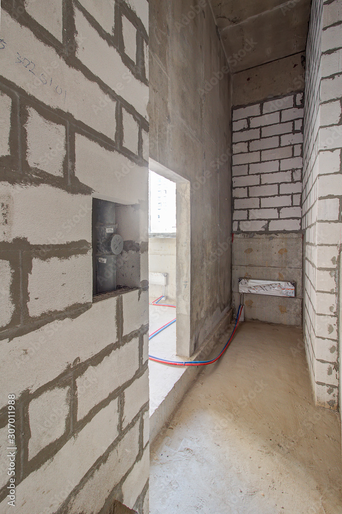Monolithic brick basement wall. heating pipes lie on floor. New empty