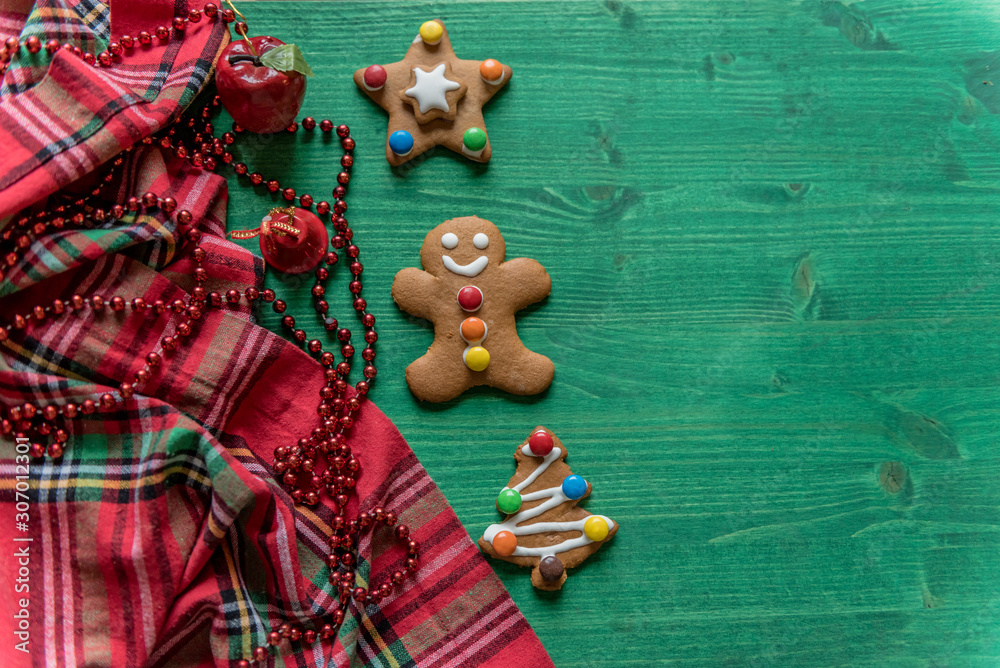 Colorful, decorated, gingerbread cookies, Christmas edition with red pearls, festive, on green wooden background  