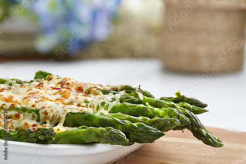 Front and close-up view of some asparagus gratin on a white fountain and unfocused background