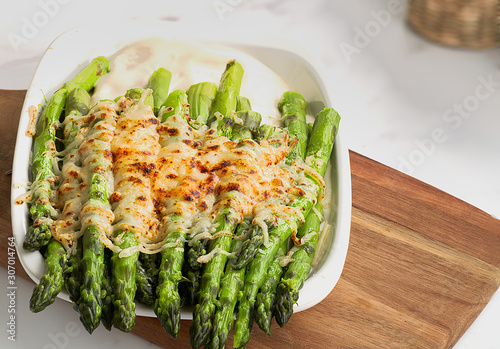 Front and close-up view of some asparagus gratin on a white fountain and unfocused background