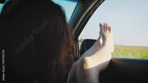 Wallpaper Mural A girl by sticking out her legs in an open window car. Young woman likes to travel by car, travel concept, lifestyle. Torontodigital.ca