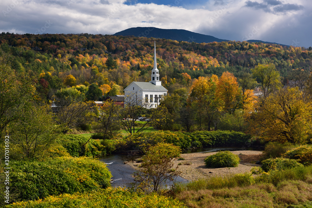 Waterbury river with Stowe Community Church against Fall color on Brush Hill in Vermont