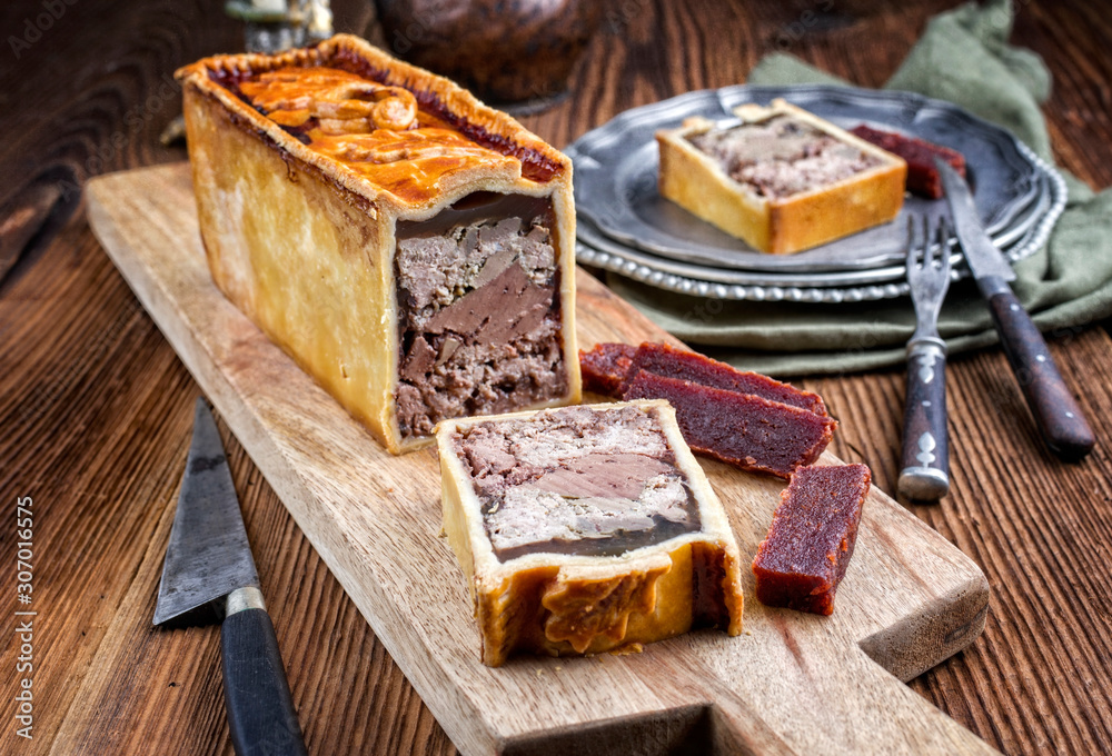 Traditional French Pate en croute with goose meat and liver ofered with quince cheese as closeup on a modern design wooden board Traditional French Pate en croute with goose meat and liver ofered with quince cheese as closeup on a modern design wooden board